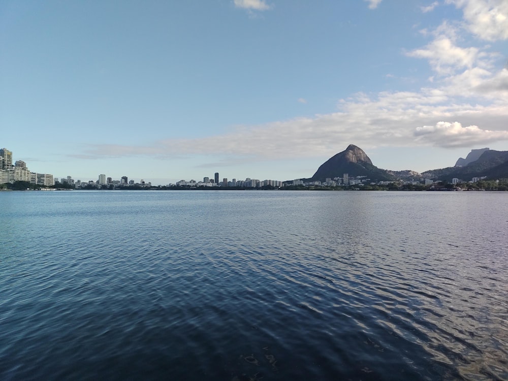 body of water near mountain under blue sky during daytime