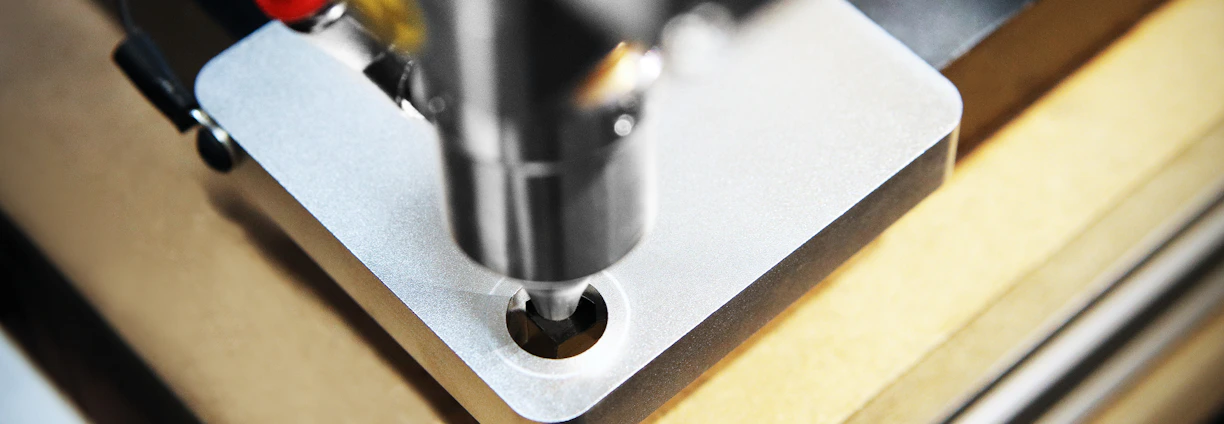 Close-up of a CNC milling machine precisely shaping a metal part in a bright workshop.