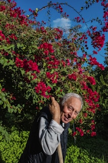 woman in black jacket standing near red flowers