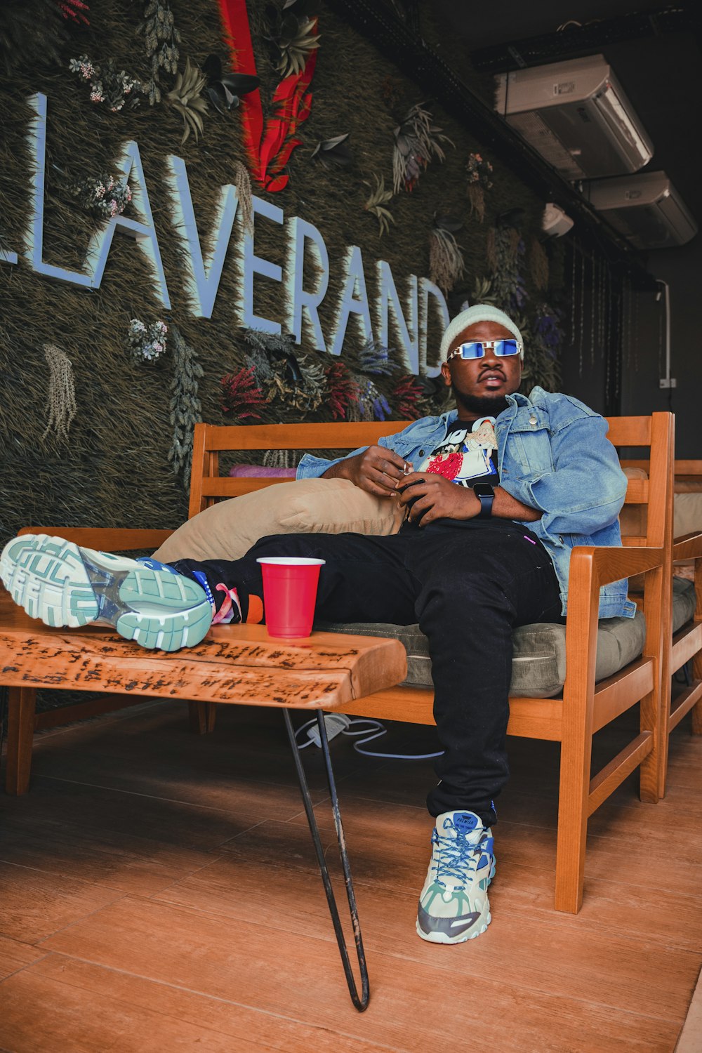 man in blue denim jacket and blue denim jeans sitting on brown wooden chair