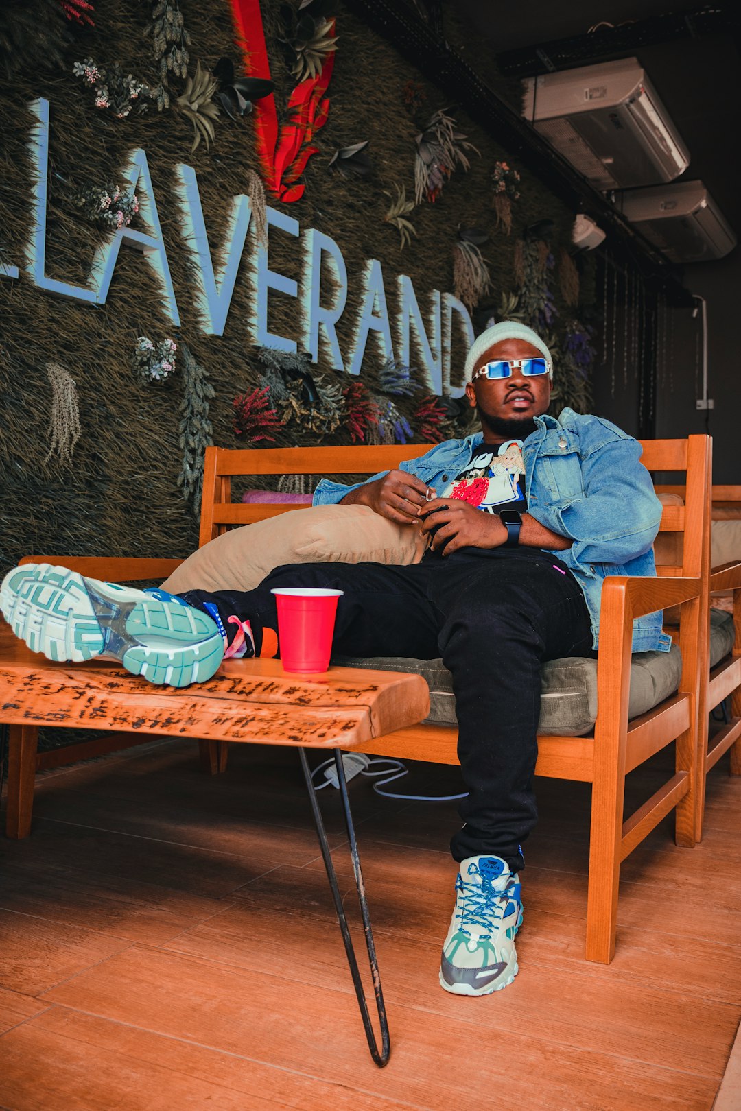 man in blue denim jacket and blue denim jeans sitting on brown wooden chair