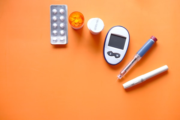 insulin pen, diabetic measurement tools and pills on orange background by Towfiqu barbhuiya