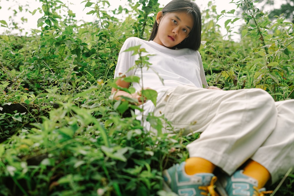 woman in white hijab and white long sleeve shirt sitting on green grass during daytime