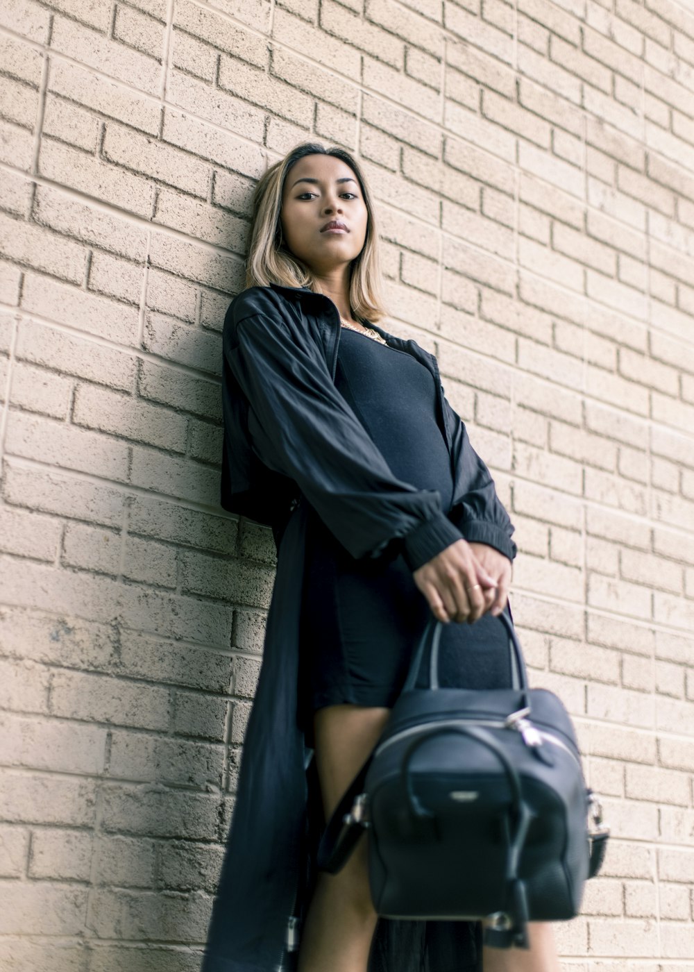 woman in black long sleeve dress leaning on wall