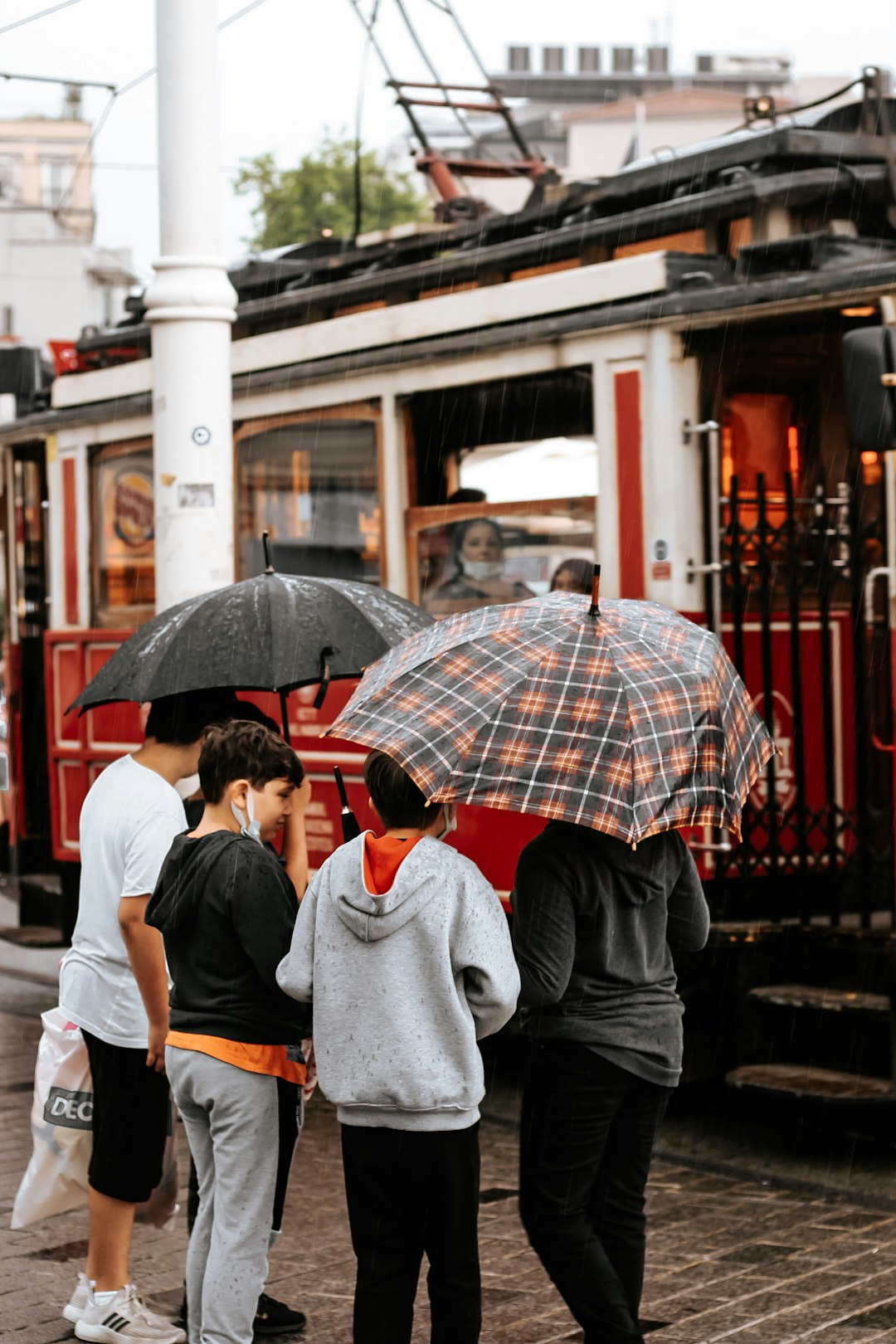 man in gray sweater holding red umbrella