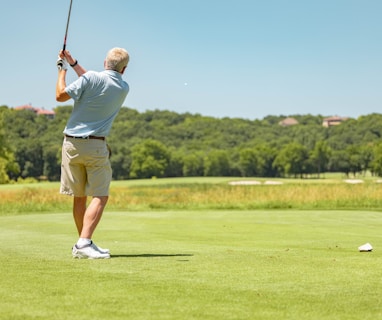 man in white t-shirt and brown shorts playing golf during daytime