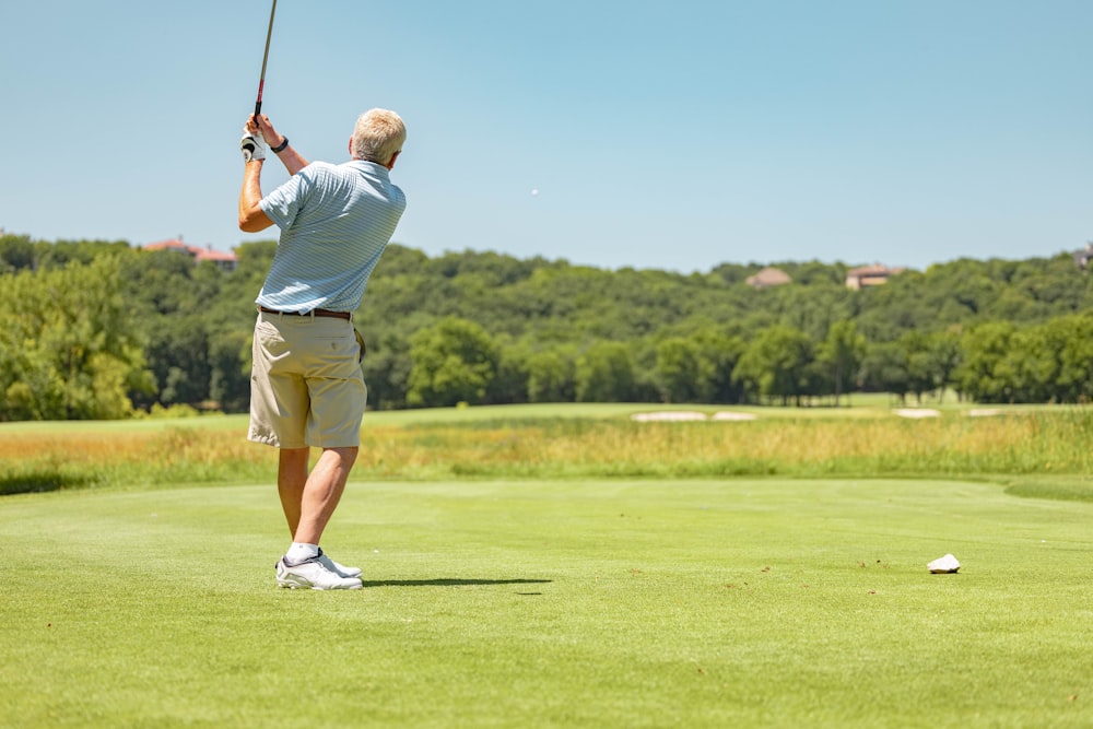 man in white t-shirt and brown shorts playing golf during daytime