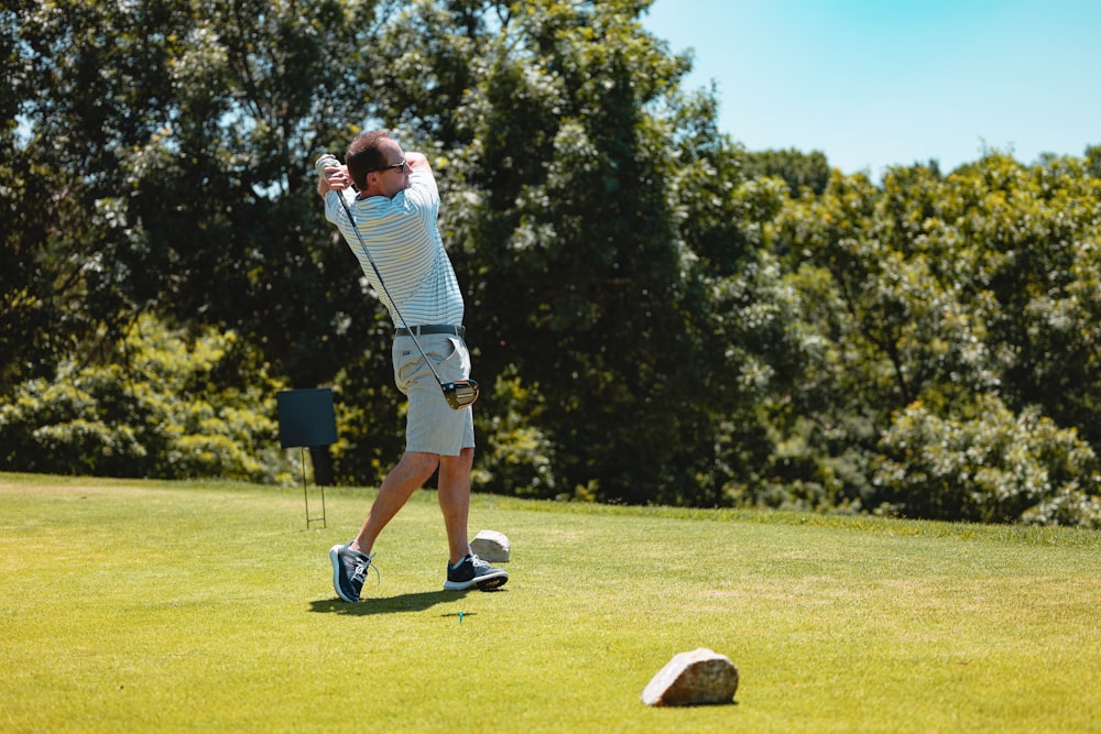 man in white and black stripe shirt playing golf during daytime