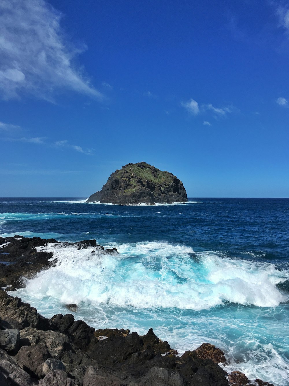 brown rock formation on sea under blue sky during daytime