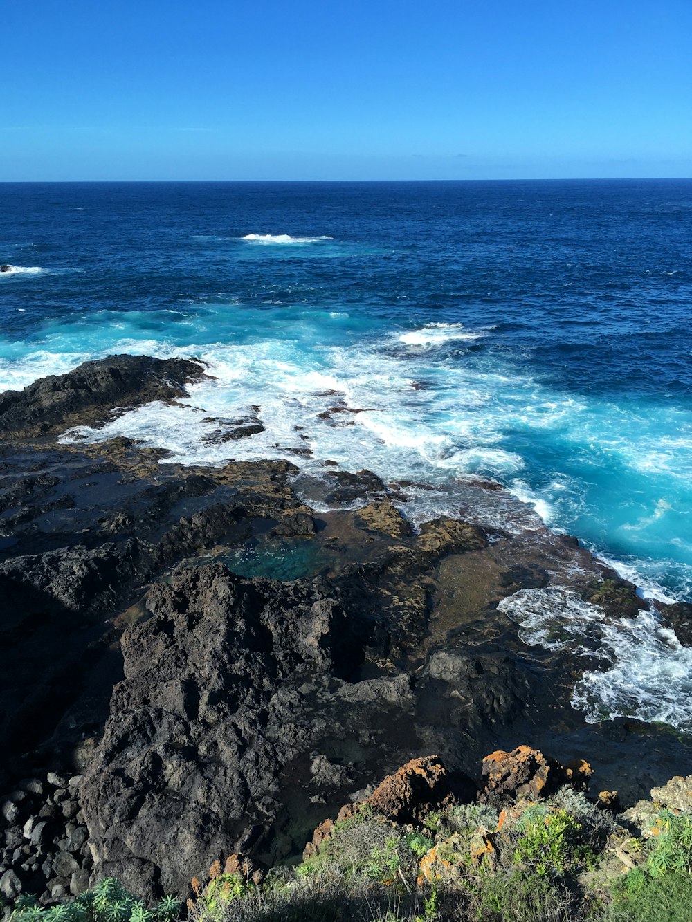 formação rochosa marrom no mar durante o dia