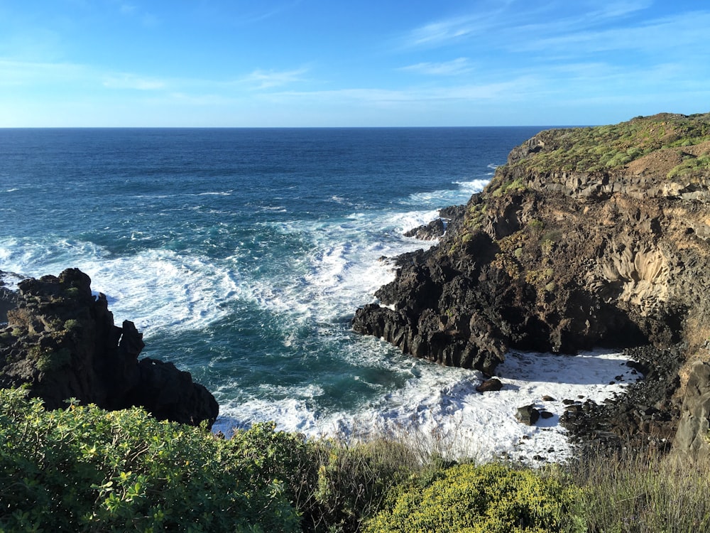 a rocky cliff overlooks the ocean on a sunny day