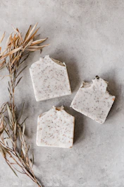 Close-up of fresh green tea leaves and natural herbal soap bars arranged on rustic wooden surface with soft natural light.
