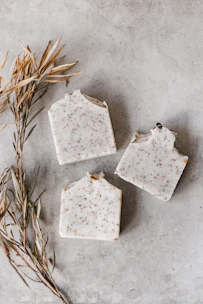 Close-up of handmade soap bars with green sage leaves on a wooden surface.