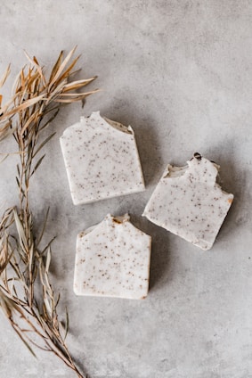 Close-up of fresh green herbs and handmade soap bars arranged on a rustic wooden surface.
