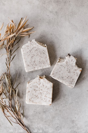 Close-up of fresh green herbs and soap bars arranged on rustic wooden surface.