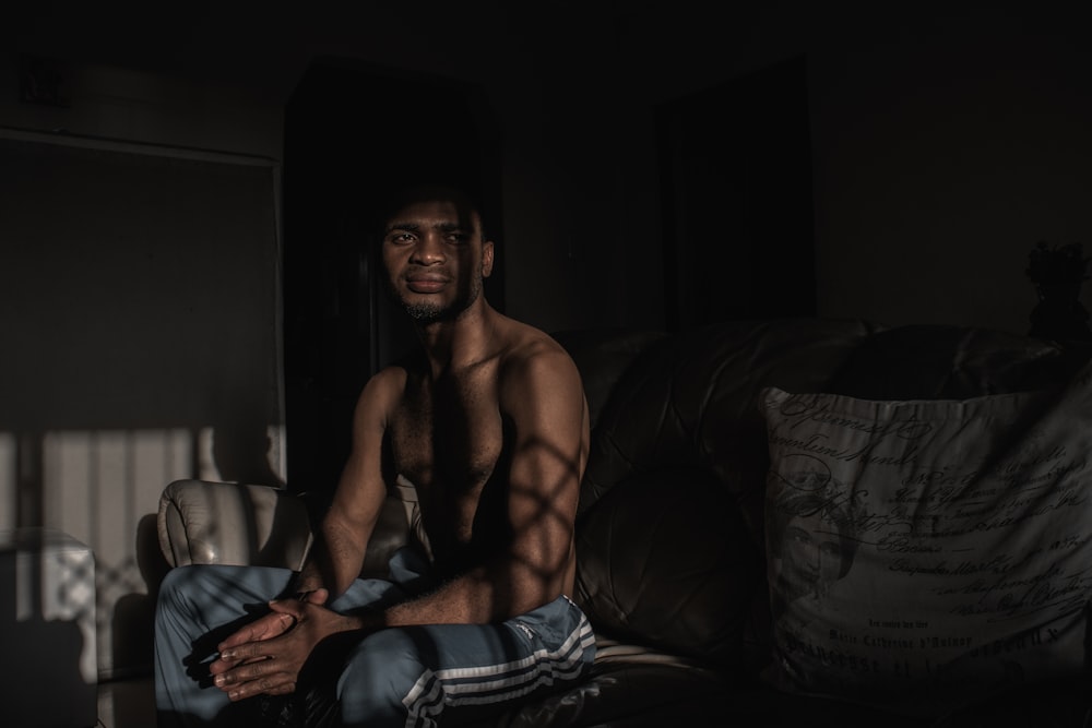 topless man sitting on black and white textile