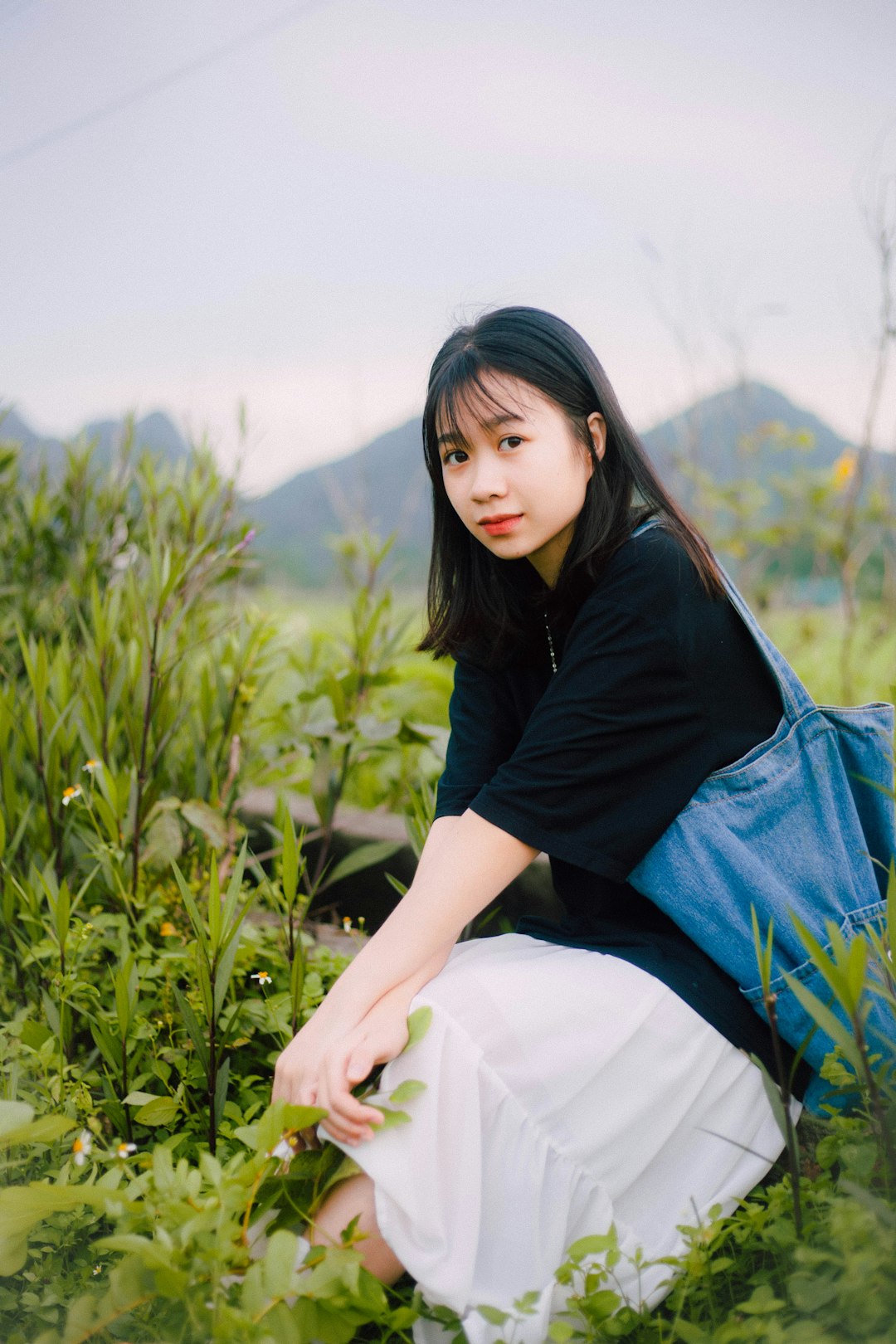 woman in black long sleeve shirt and white skirt sitting on green grass field during daytime