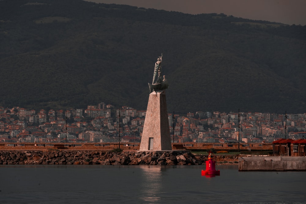 Phare en béton blanc et gris près d’un plan d’eau pendant la journée