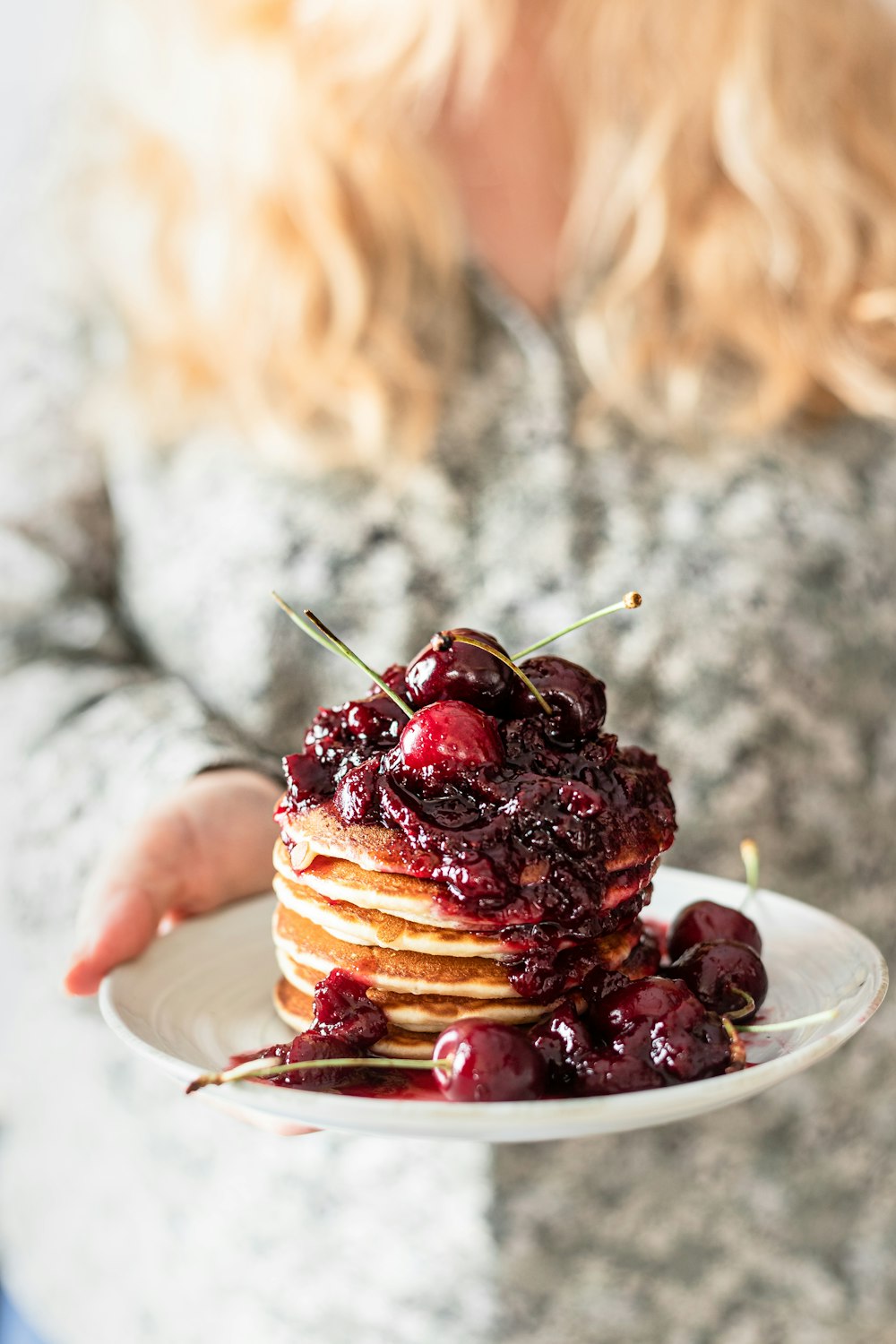 personne tenant une assiette de crêpes aux fruits rouges