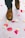 A pair of brown leather dress shoes on a patterned white surface with scattered rose petals in various shades of pink and yellow.