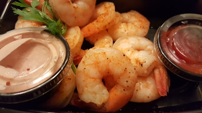 Close-up of spicy boiled shrimp and sausage resting on newspaper-covered picnic table.