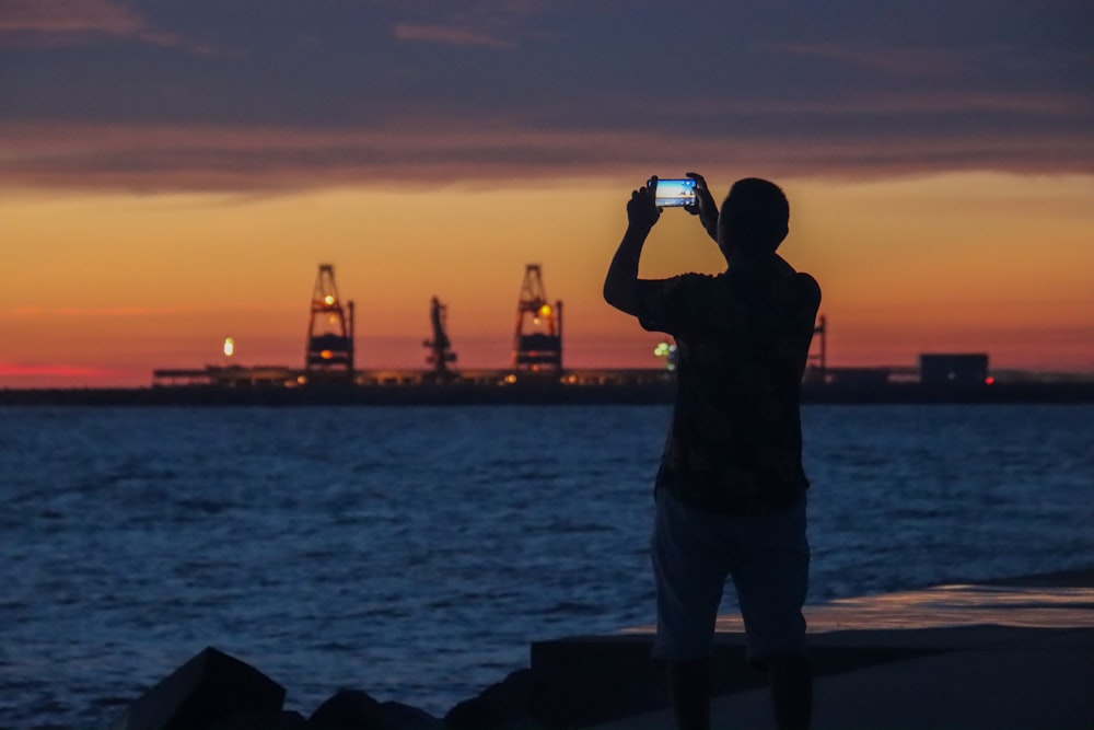 silhouette of man standing on rock formation during sunset