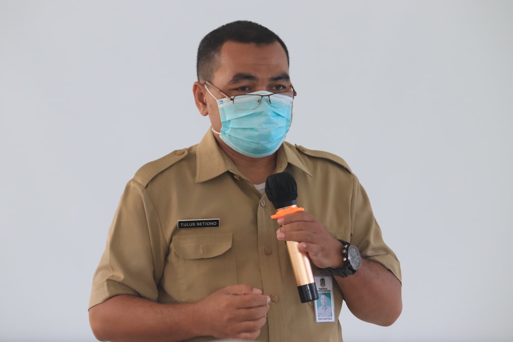 man in brown button up shirt holding white and black bottle