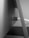A close-up view of a cable connected through a cylindrical holder attached to a flat surface. The image is in black and white, highlighting the contrast between the smooth surfaces of the cable and the holder.