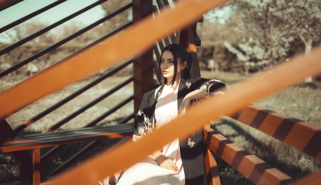 woman in white and black shirt sitting on orange and black metal stair railings during daytime