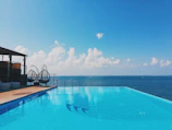 Infinity pool reflecting the clear blue sky beside a sleek yacht dock.