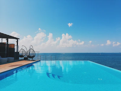 Infinity pool reflecting the clear blue sky beside a sleek yacht dock.