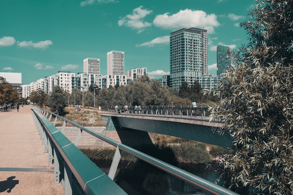 green metal bridge over river near city buildings during daytime