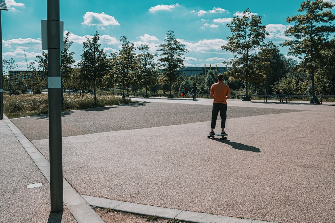 man in orange jacket walking on gray concrete road during daytime