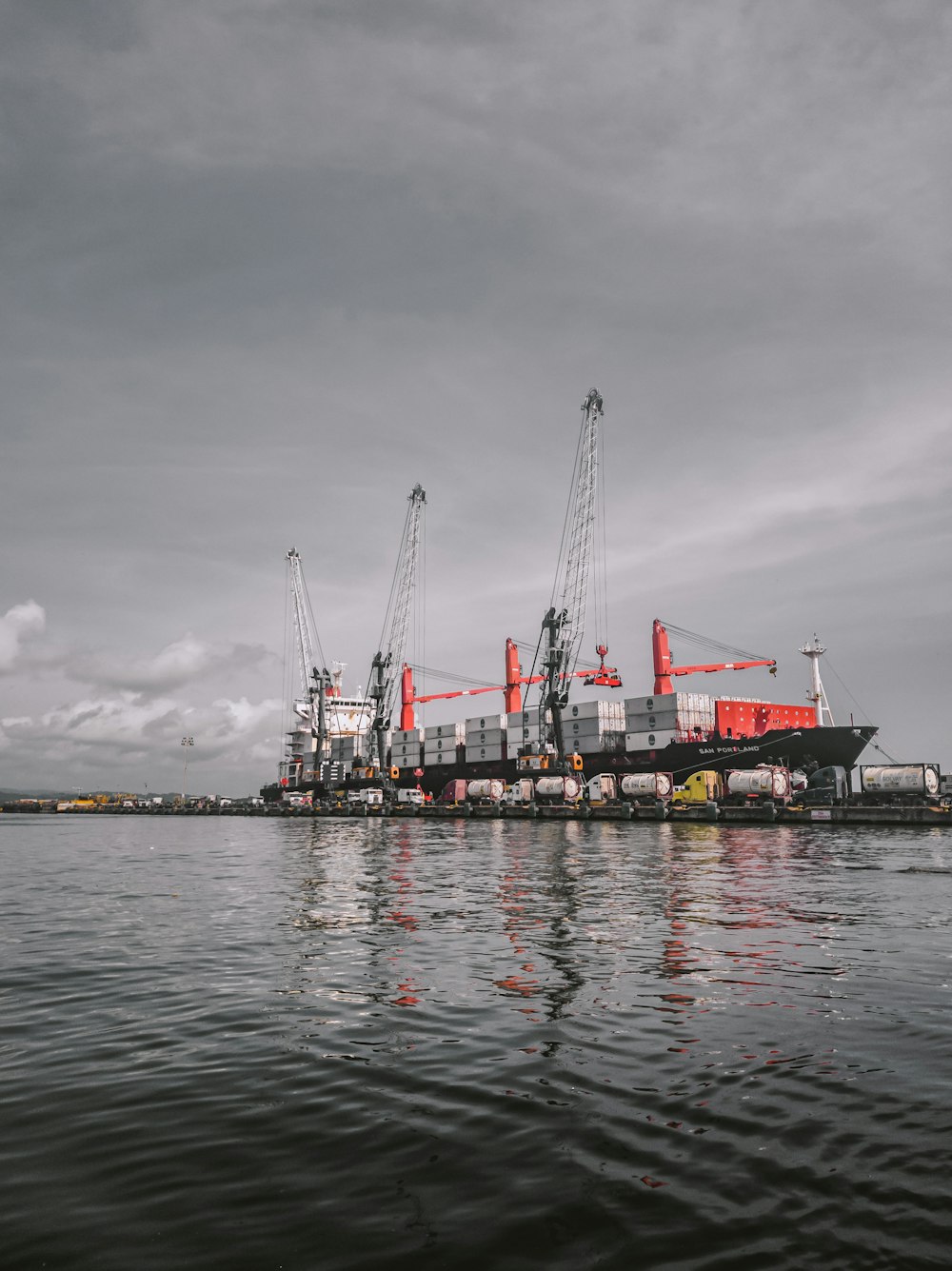 red and white cargo ship on sea under gray sky