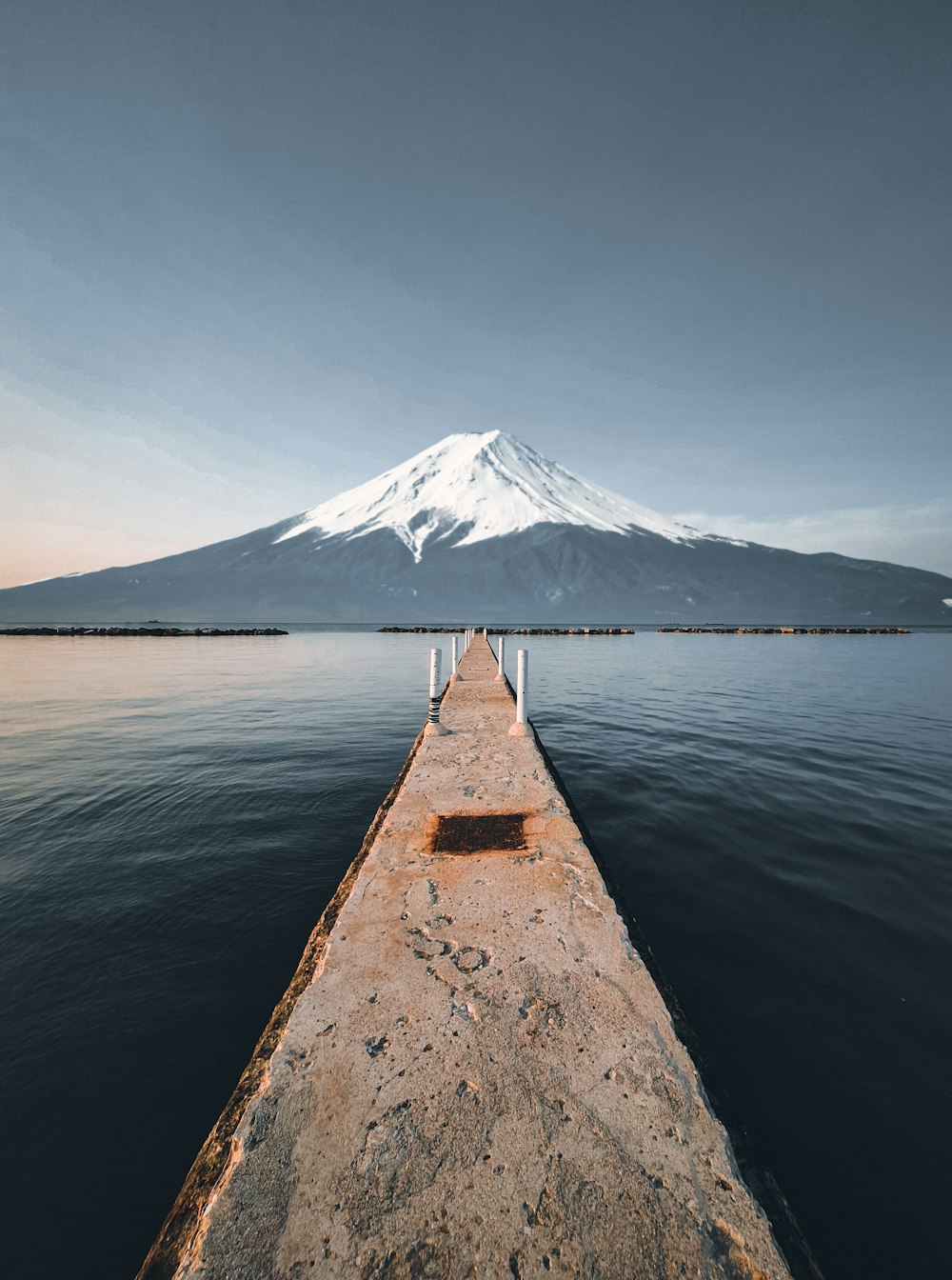 person standing on brown wooden dock near body of water during daytime