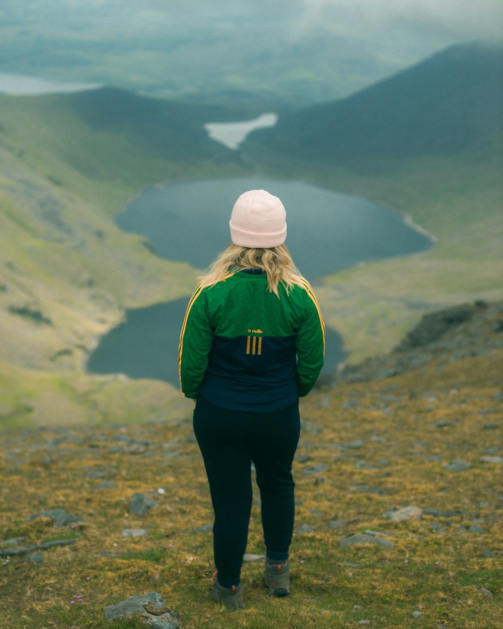 person in green jacket and black pants standing on brown field during daytime