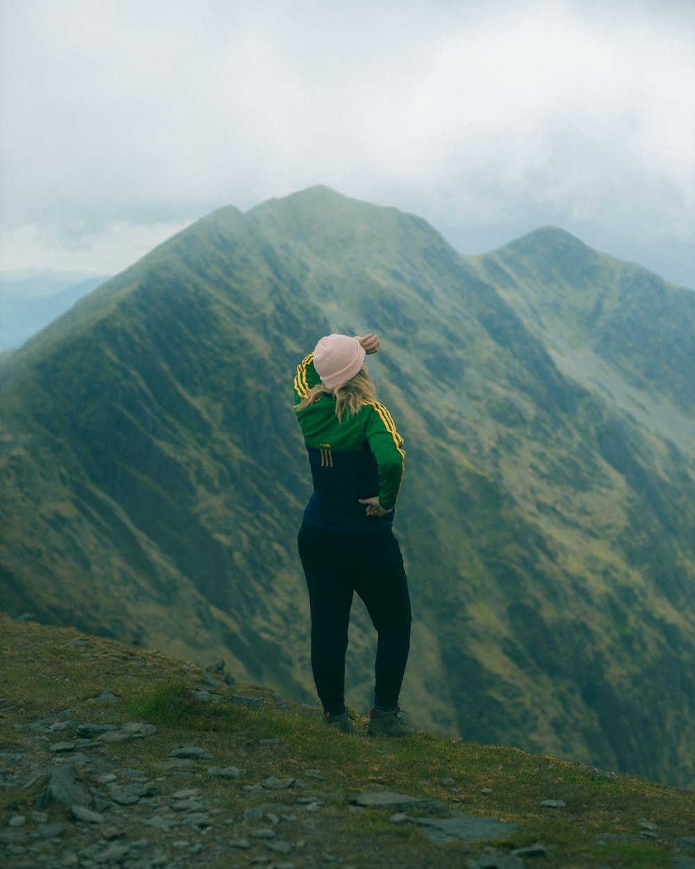 woman in green hoodie standing on top of mountain during daytime