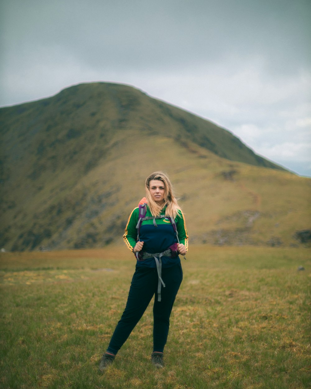 woman in green long sleeve shirt and black pants standing on green grass field during daytime