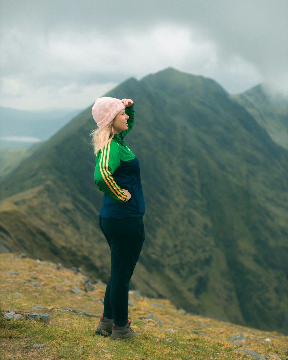 woman in green jacket standing on brown rock formation during daytime