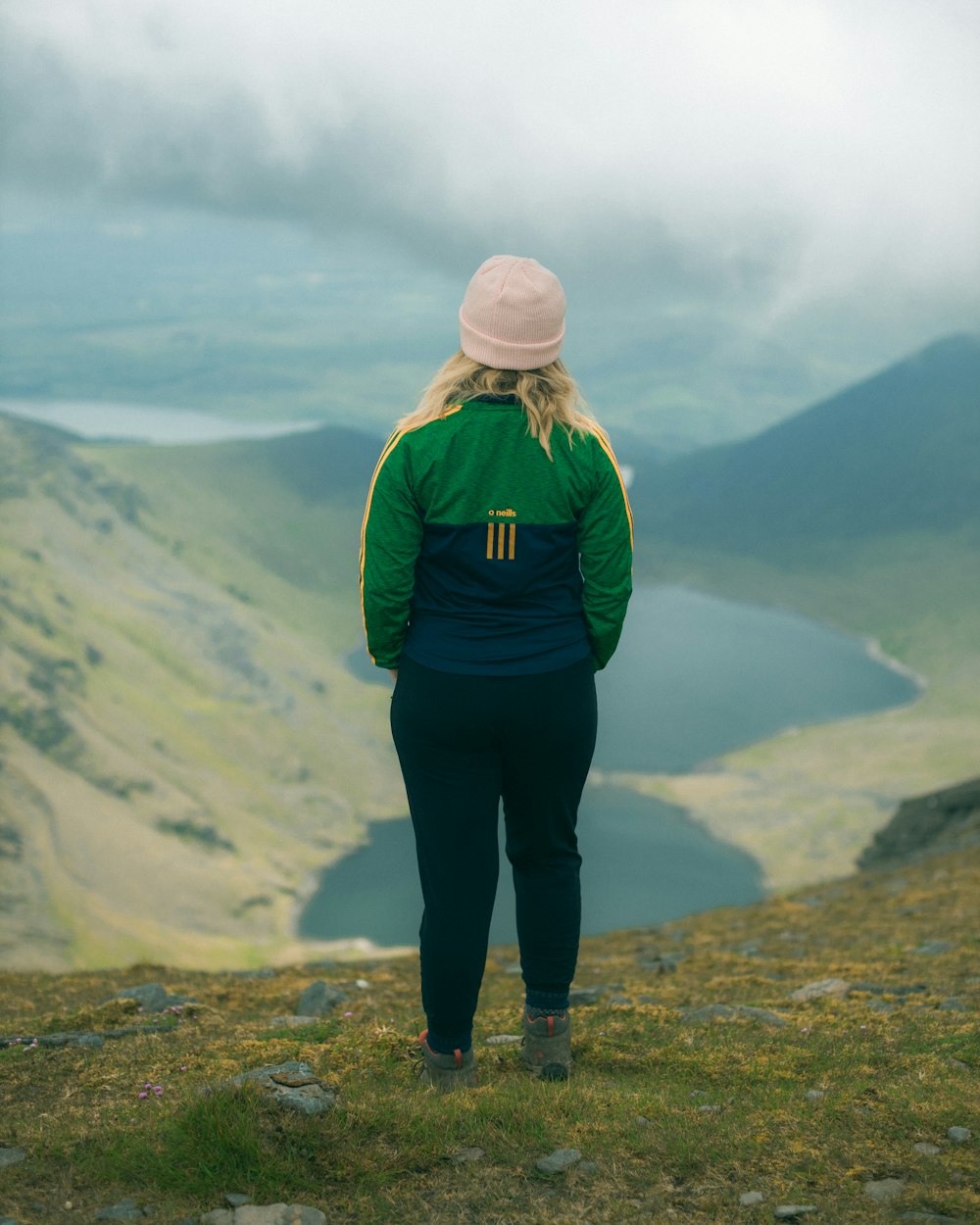 woman in green jacket standing on top of mountain during daytime