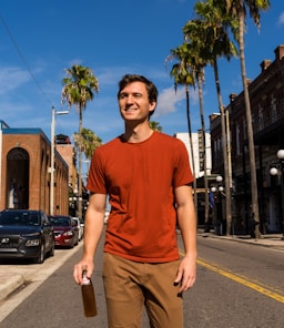 man in blue crew neck t-shirt and brown pants standing on sidewalk during daytime