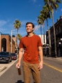 man in blue crew neck t-shirt and brown pants standing on sidewalk during daytime