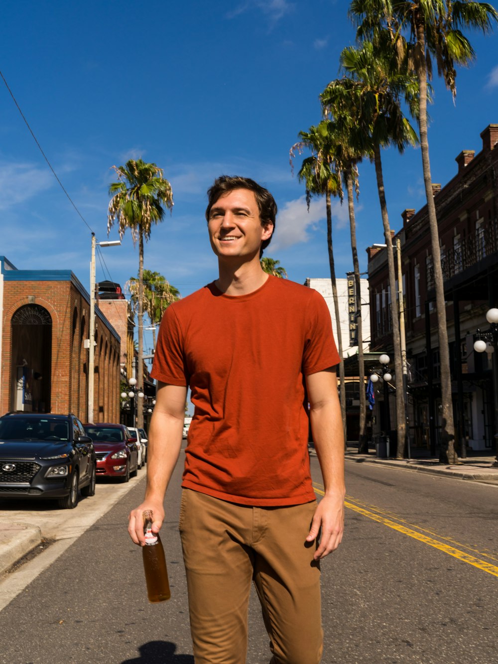 man in blue crew neck t-shirt and brown pants standing on sidewalk during daytime