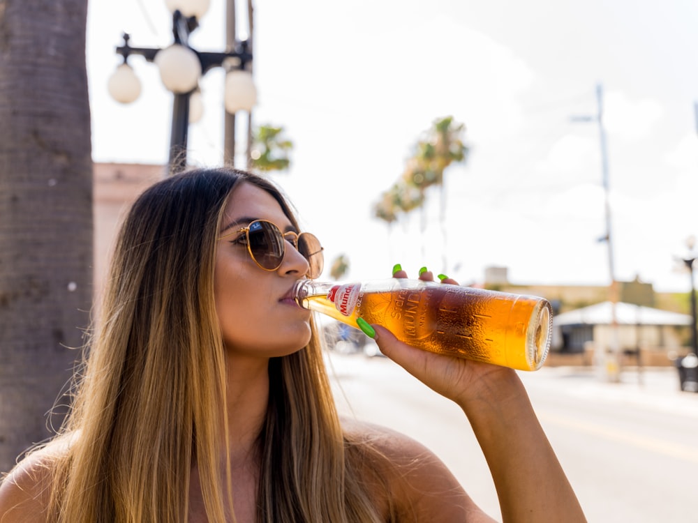 Donna che beve birra su un boccale di vetro trasparente durante il giorno