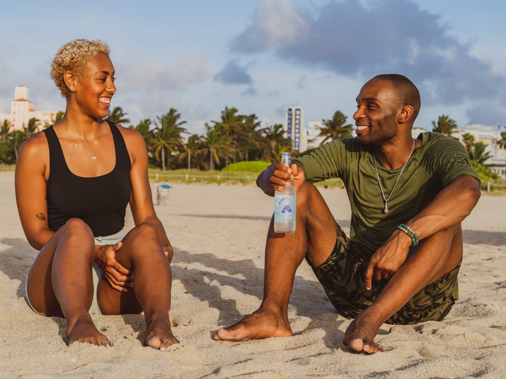 man and woman sitting on sand during daytime