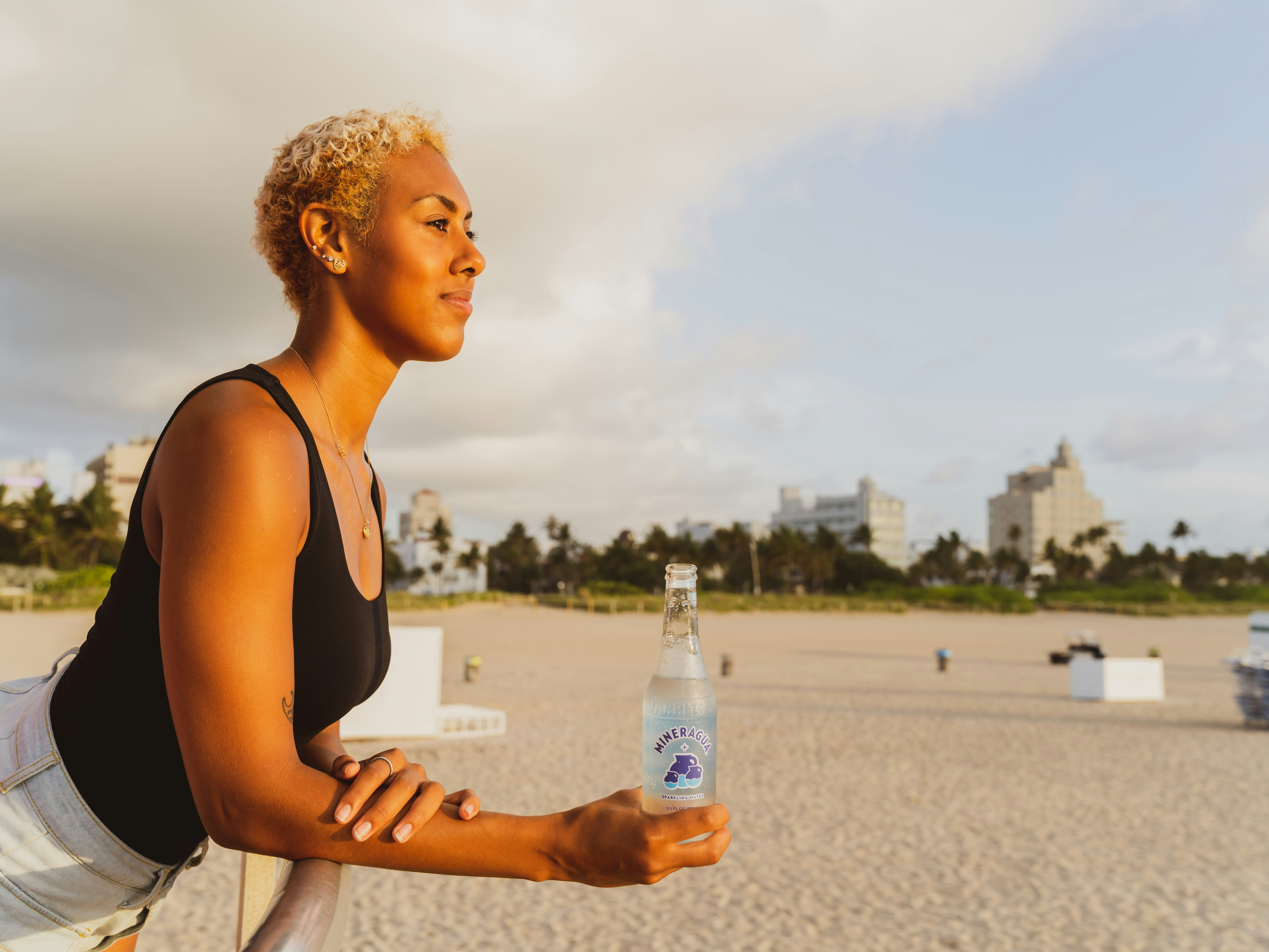 mujer en camiseta sin mangas negra sosteniendo agua embotellada