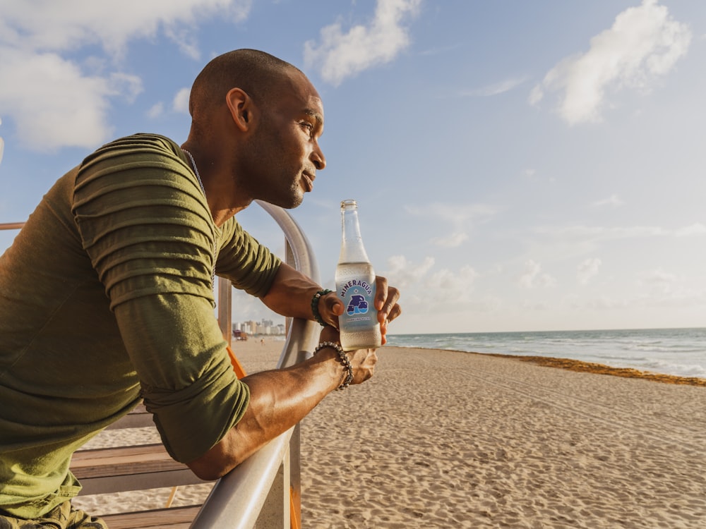 man in green and white striped long sleeve shirt drinking water from bottle