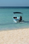 man in black shirt sitting on white and blue boat on sea during daytime