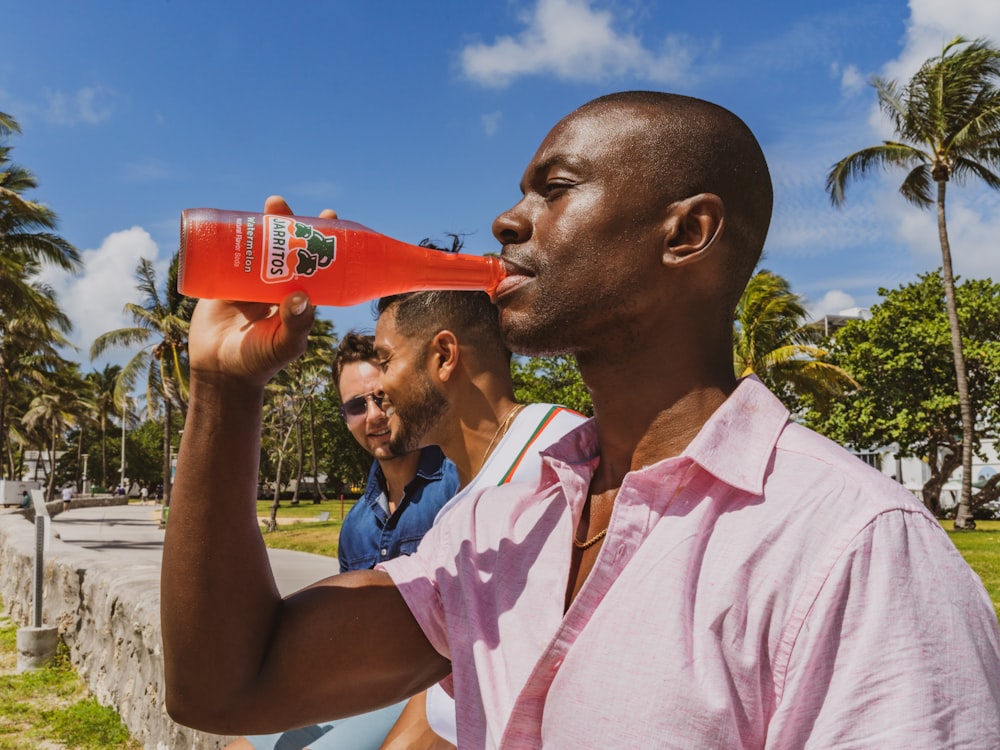 man in pink polo shirt drinking from red can