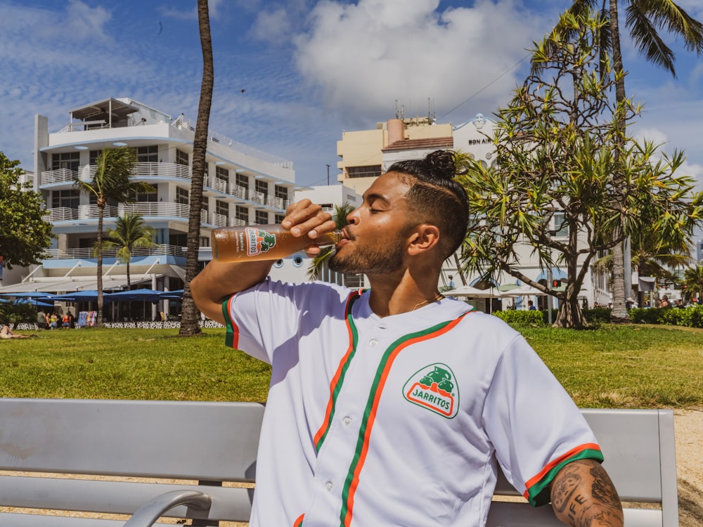 man in white and red nike crew neck t-shirt smoking cigarette during daytime